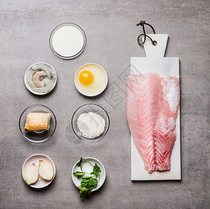 碗中鱼片的各种烹饪原料鱼片鸡蛋虾洋葱包灰色石头背景上的粉顶部视图图片