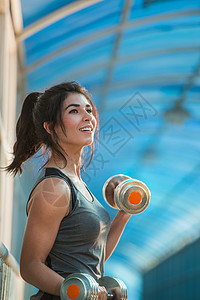 运动的女人城市的户外用哑铃泵肌肉图片