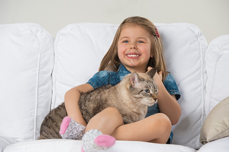 看着远方的猫可爱的小女孩抱着塔比猫,看着远方背景