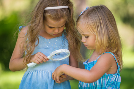 带放大镜的孩子两个小妹妹的朋友透过放大镜看花图片
