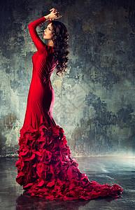轻苗条感时尚女人穿着红色长裙站石墙背景上图片