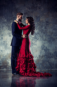 轻优雅的情侣穿着晚礼服肖像穿红色衣服的女人穿黑色西装的男人拥抱图片