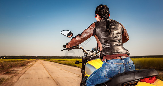 骑摩托车的骑自行车的女孩穿着皮夹克头盔背景图片