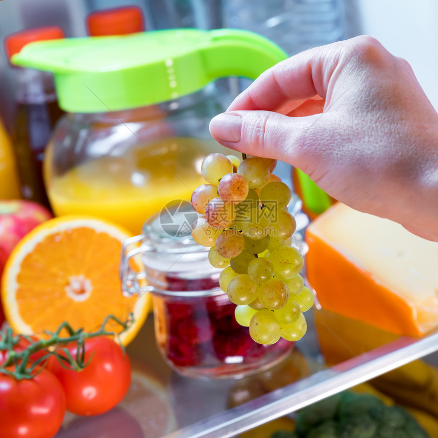 女人敞开的冰箱里出串葡萄健康的食物图片