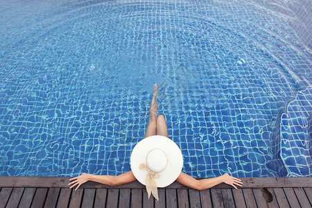戴大帽子的女人游泳池里放松女人戴着大帽子游泳池里背景图片