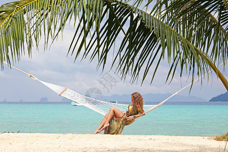 热带海滩上的女人美丽的轻女人穿着比基尼热带海滩的吊床上图片