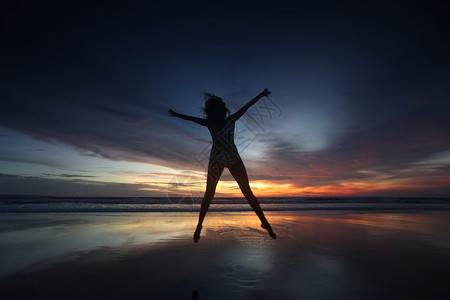 快乐的女人日落时跳海滩上,巴厘岛,塞米尼亚克,双六海滩背景图片