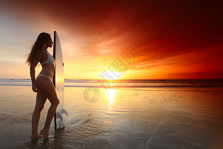 日落时海滩上的冲浪女孩日落时海滩上美丽的冲浪女孩背景图片