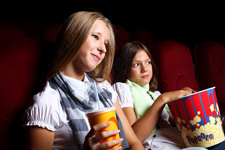 女孩坐椅子两个轻女孩电影院看电影背景