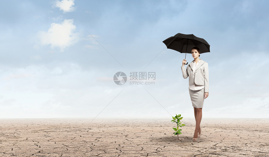 环境保护吸引力的女商人用雨伞保护绿芽图片
