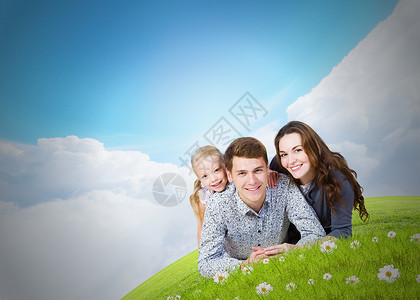 轻的家庭幸福的三口之家躺绿色的草地上图片