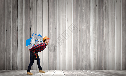 建筑工人带着房子轻的建筑工人戴着安全帽,背上背着房屋模型图片