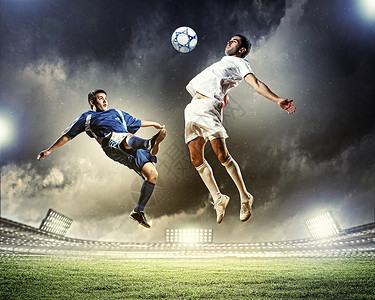 两名足球运动员击球两名足球运动员体育场跳以击球高清图片