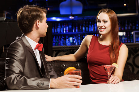 优雅的酒吧里轻英俊的男人,伴随着优雅的女士背景图片