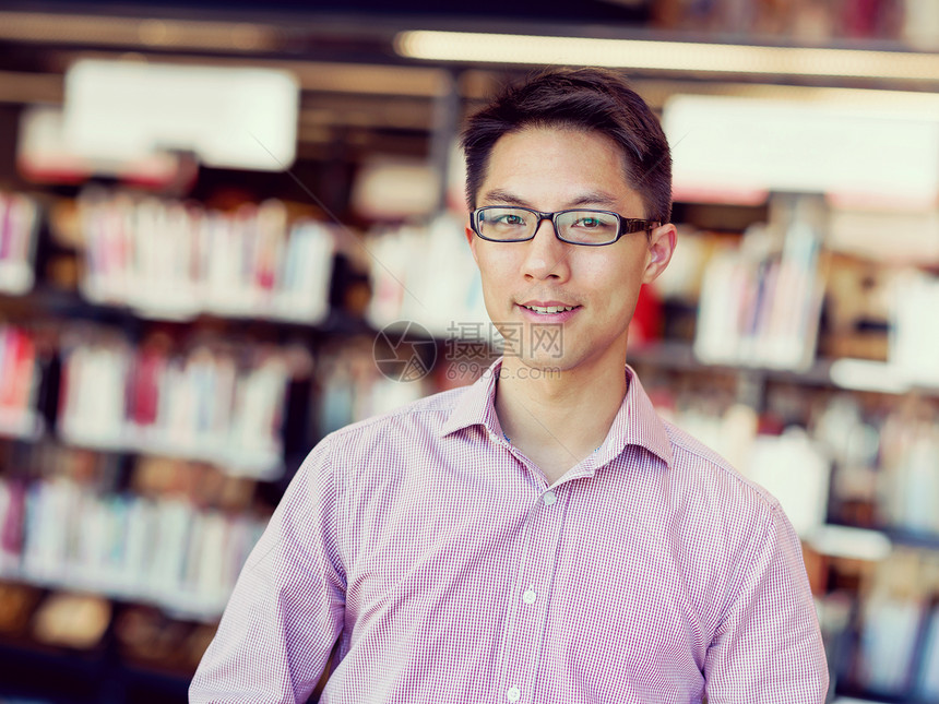 图书馆里快乐的男学生快乐的亚洲男学生戴着眼镜站图书馆图片