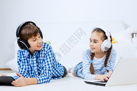可爱的孩子用设备男孩女孩躺地板上用平板电脑笔记本电脑图片
