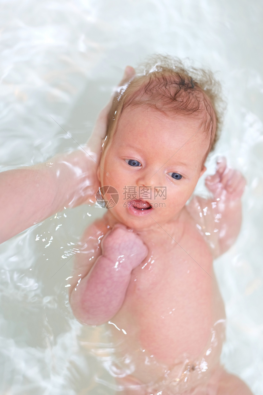 新生儿父亲的帮助下浴缸里游泳图片
