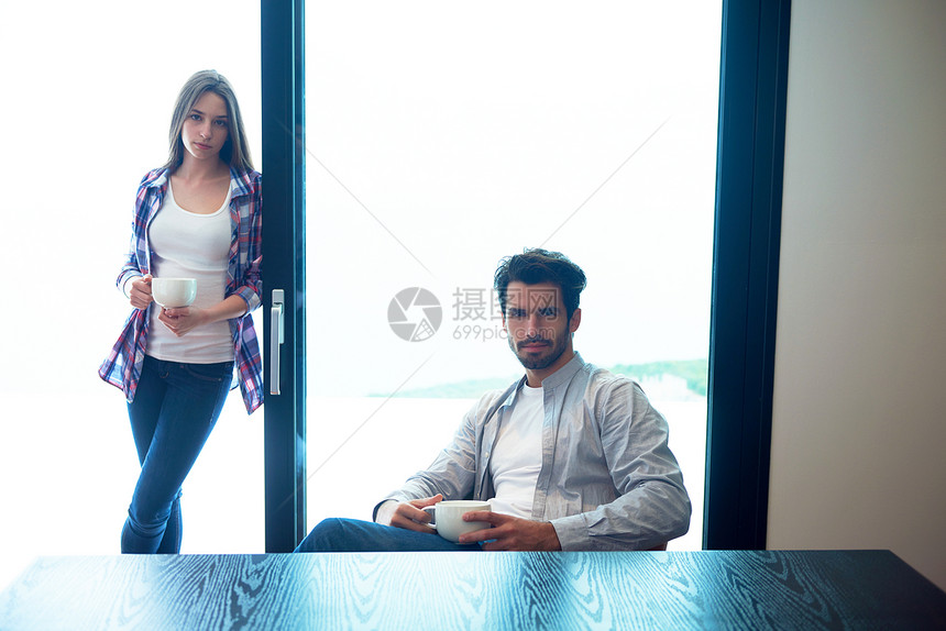 放松的轻夫妇喝天早上的咖啡,大明亮的窗户现代家庭别墅内部图片