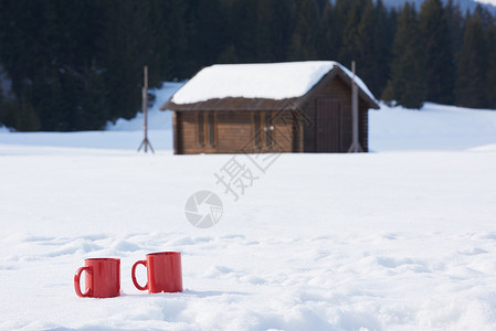 两辆红色的热茶饮料雪中,美丽的冬季阳光明媚的天,与木屋森林的背景蒸汽高清图片素材