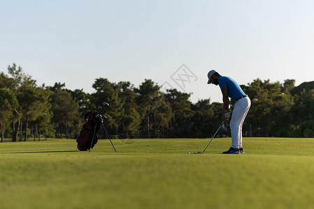 高尔夫球手美丽的日落时与司机球场上打远射图片