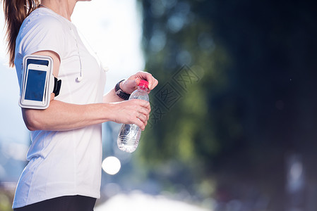 轻女子喝水后,莫尼格慢跑锻炼城市日出背景图片