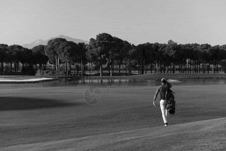 背着手交警英俊的中东高尔夫球手背着包,走高尔夫球场的下个洞背景