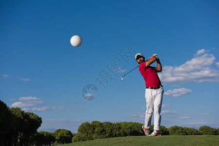 高尔夫球手击球与司机球场上美丽的晴天背景图片