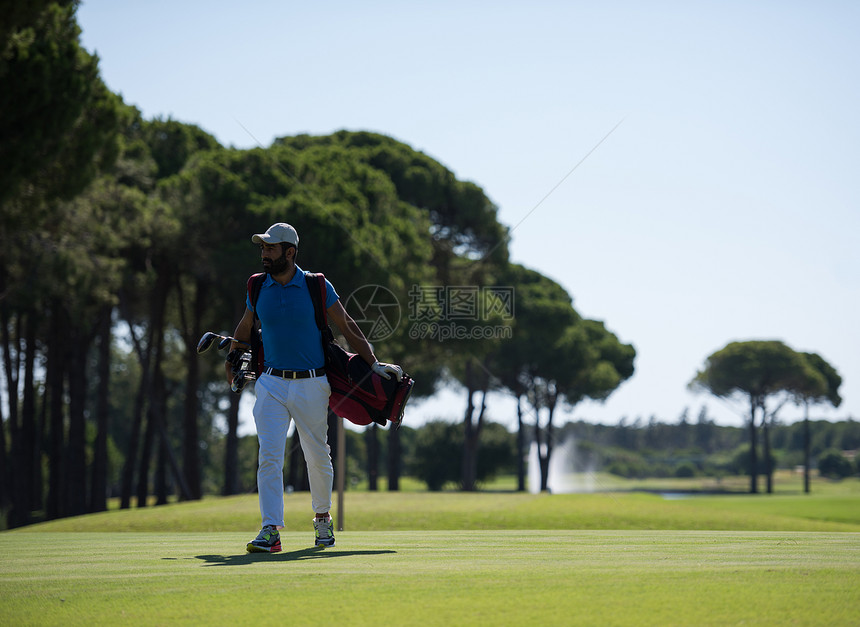 英俊的中东高尔夫球员背着包,球场上走下个洞图片