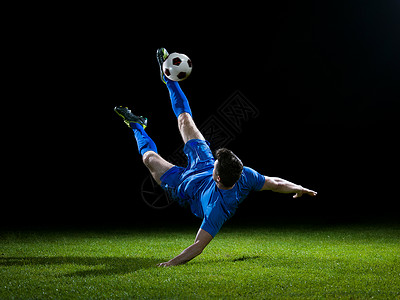 足球运动员足球场上踢球,黑色背景上被隔离高清图片