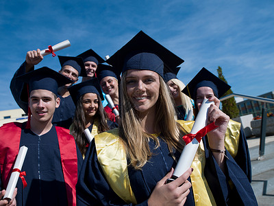 毕业日,轻的毕业生们站大学大楼前成就高清图片素材