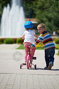 快乐的孩子们户外,哥哥姐姐公园玩得开心公园里的男孩女孩学骑自行车图片