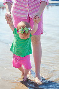 快乐的妈妈宝宝海滩上玩得开心,同时学会走路迈出步高清图片