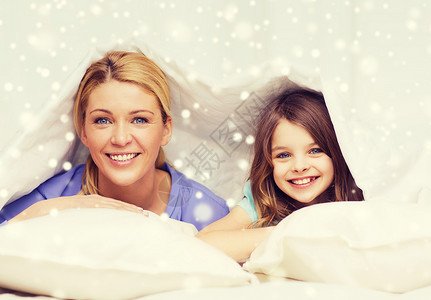 家庭,孩子,舒适,床上用品家庭快乐的母亲女孩毛毯下雪花背景图片