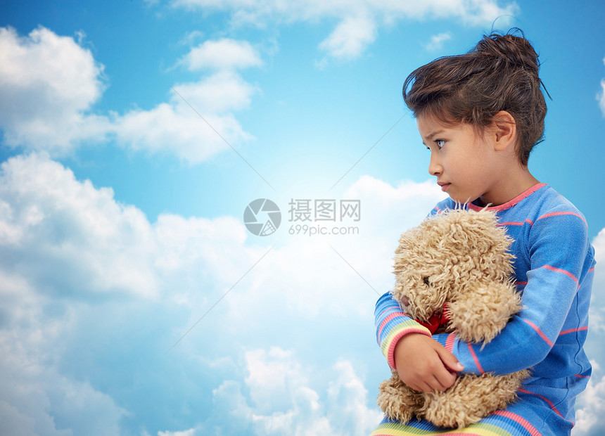 童,悲伤,孤独人的悲伤的小女孩带着泰迪熊玩具蓝天云彩的背景上图片