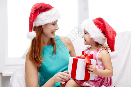 诞节,假期,家庭,童人的快乐的母亲小女孩戴着诞帽,家里礼品盒背景图片