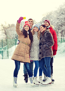 人友谊技术休闲理念快乐的朋友户外滑冰场上用智能手机自拍图片