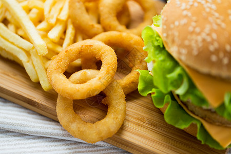快餐,垃圾食品健康的饮食汉堡奶酪汉堡,油炸鱿鱼圈薯条木桌上图片