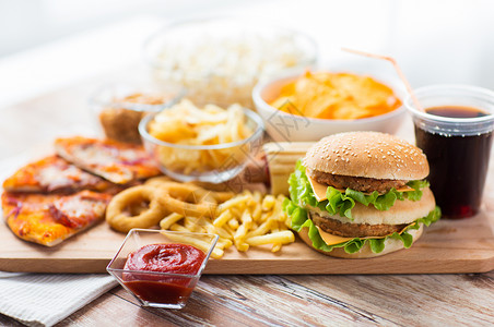 快餐健康的饮食汉堡芝士汉堡,油炸鱿鱼圈,炸薯条,饮料番茄酱木桌上图片