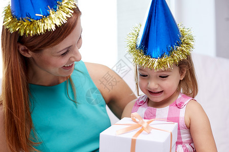 假期,生日家庭,童人的快乐的母亲小女孩戴着派帽,家里礼品盒图片