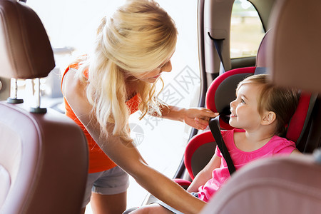 家庭,交通,安全,道路旅行人们的快乐的母亲系紧孩子的汽车安全带图片