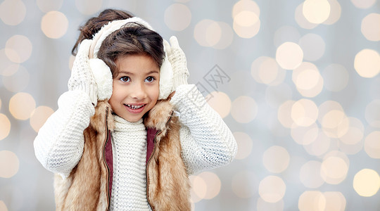 冬天,人们,诞节,时尚童的快乐的小女孩戴着耳罩手套节日的灯光背景背景图片