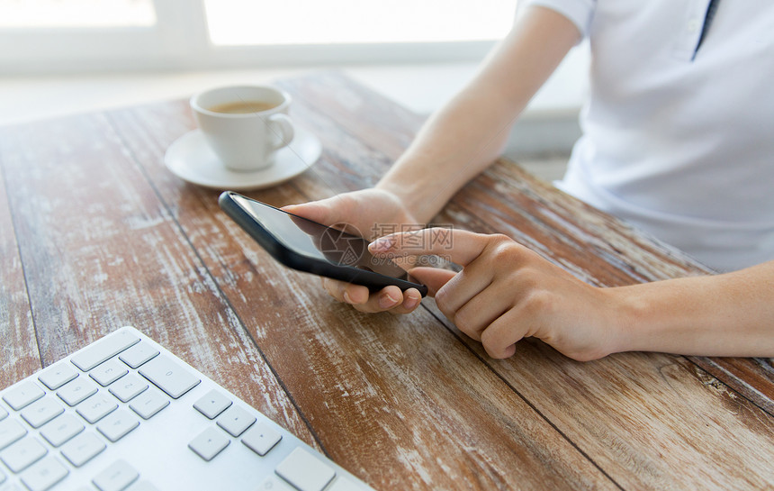 商业,技术人的近距离的男手智能手机与咖啡键盘木桌上图片