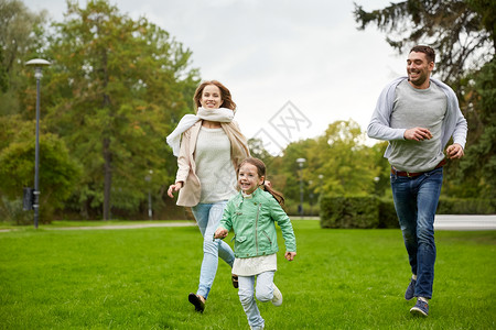 母亲父亲小女孩在夏天的公园里跑步玩接球游戏父母身份高清图片素材