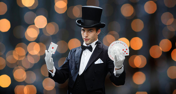 黑色扑克牌问号魔术,表演,赌场,人表演魔术师顶帽魔术与扑克牌近光灯背景背景