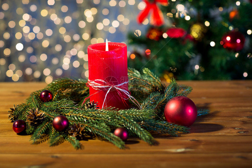 诞节装饰假日广告木板上用红色燃烧蜡烛天然绿色冷杉枝花环