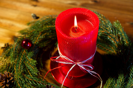 诞节装饰假日广告木板上用红色燃烧蜡烛天然绿色冷杉枝花环火焰高清图片素材