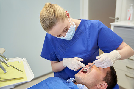 人,医学,口腔医学保健女牙医用牙科镜检查男病人的牙齿牙科诊所办公室图片