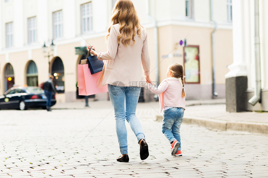 销售,消费主义人的密切母婴与购物袋走城市街道图片