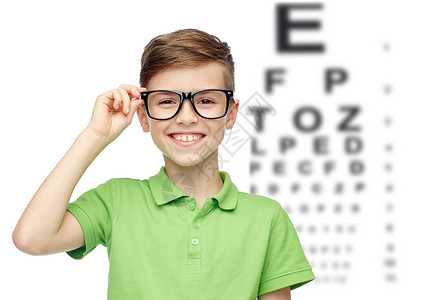 童,视力,视力人的快乐的微笑男孩绿色马球T恤眼镜上的眼睛图表背景图片