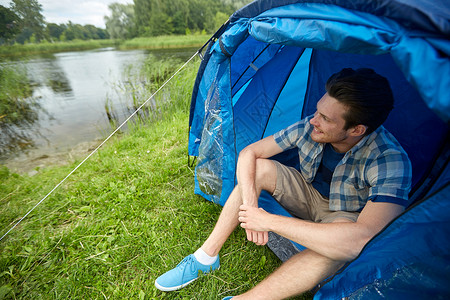 旅行,旅游,徒步旅行,设备人的快乐的轻人坐帐篷里露营湖边河岸图片